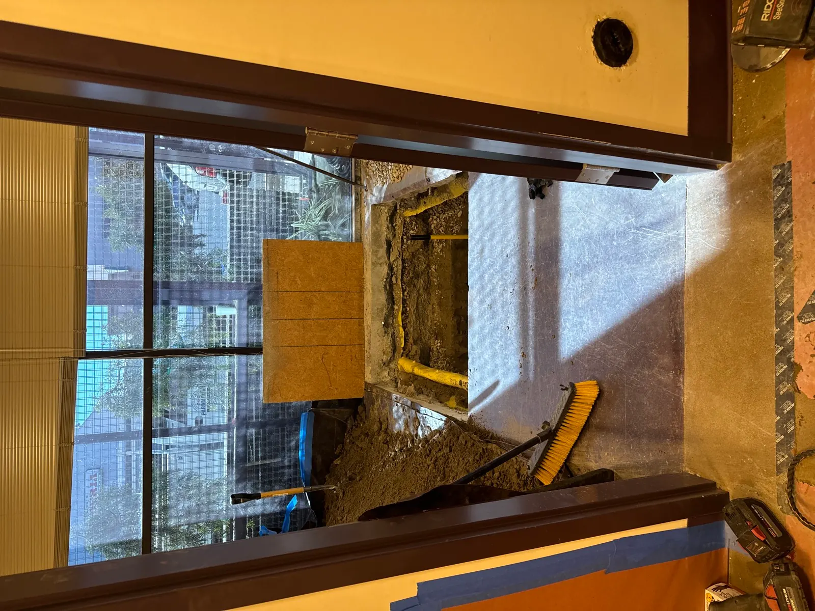Interior under-slab excavation exposing new sewer piping just inside a commercial tenant entrance